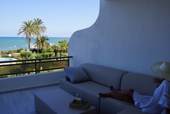 A balcony with a view of the sea, a white sofa, and a small table with a bottle. - Fantastic sea views right on the beach in Denia (Denia)