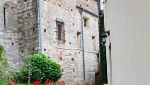 Un sendero de piedra que conduce a un edificio con un muro de piedra y flores rojas.