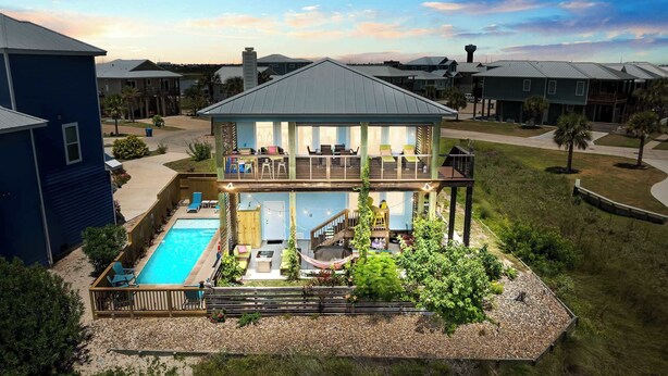 Una casa de dos pisos con piscina, mobiliario exterior y terraza.