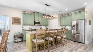 Una cocina con armarios verdes, un refrigerador de acero inoxidable y una zona de comedor de madera.