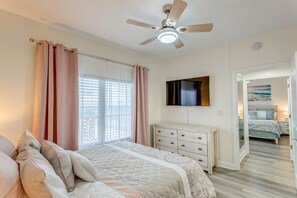 Ein Schlafzimmer mit einem Bett, einem Schminktisch, einem Deckenventilator und einem Fernseher an der Wand.