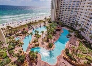Ein Resort mit großzügigem Poolbereich, umgeben von Palmen und Blick auf den Strand.