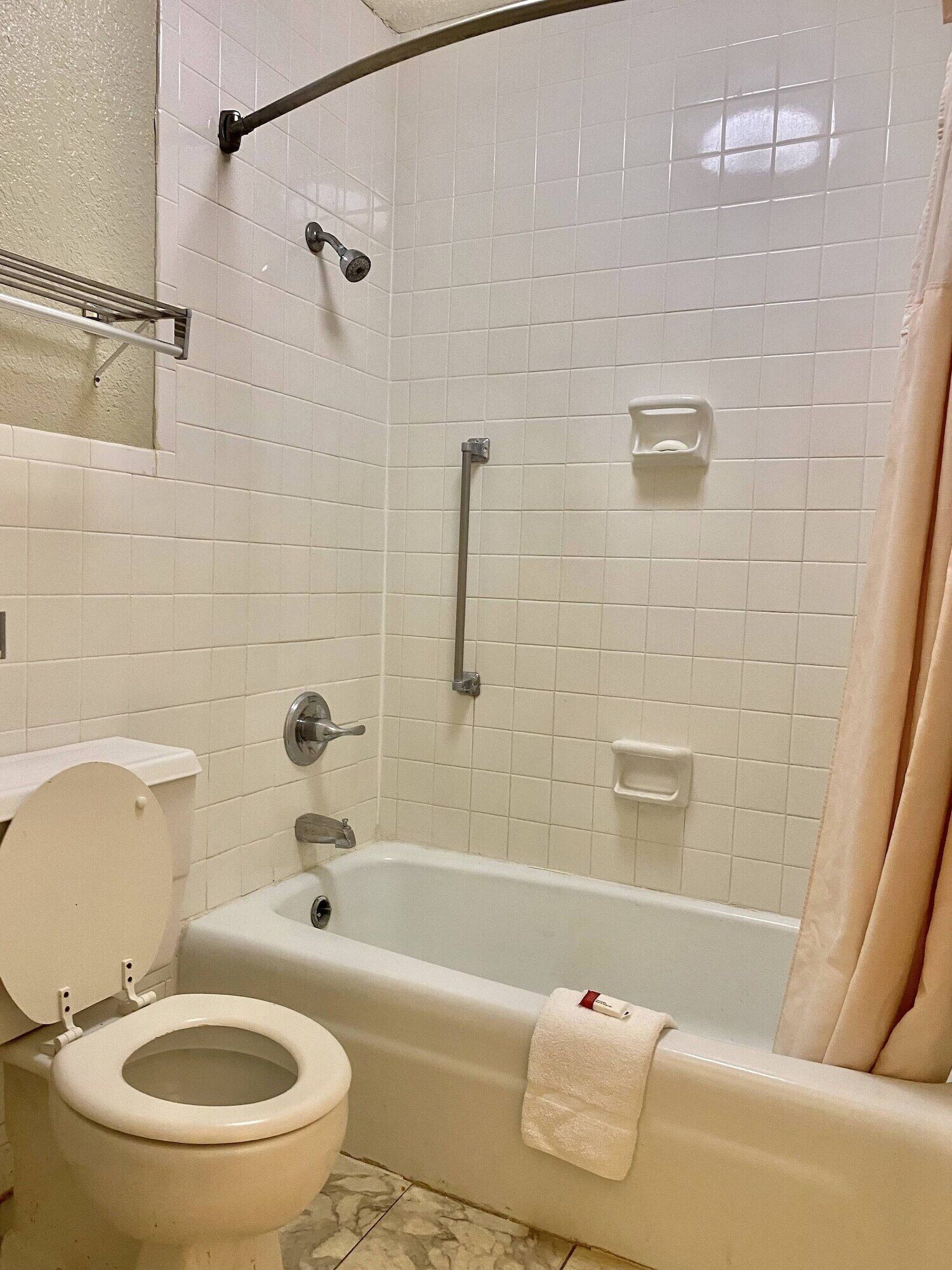 A bathroom with a bathtub, toilet, and shower area.