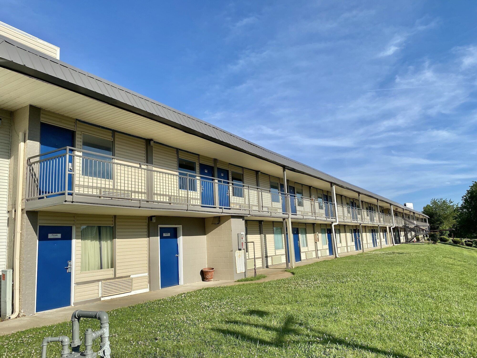 A motel with multiple rooms, each with a balcony and a blue door.