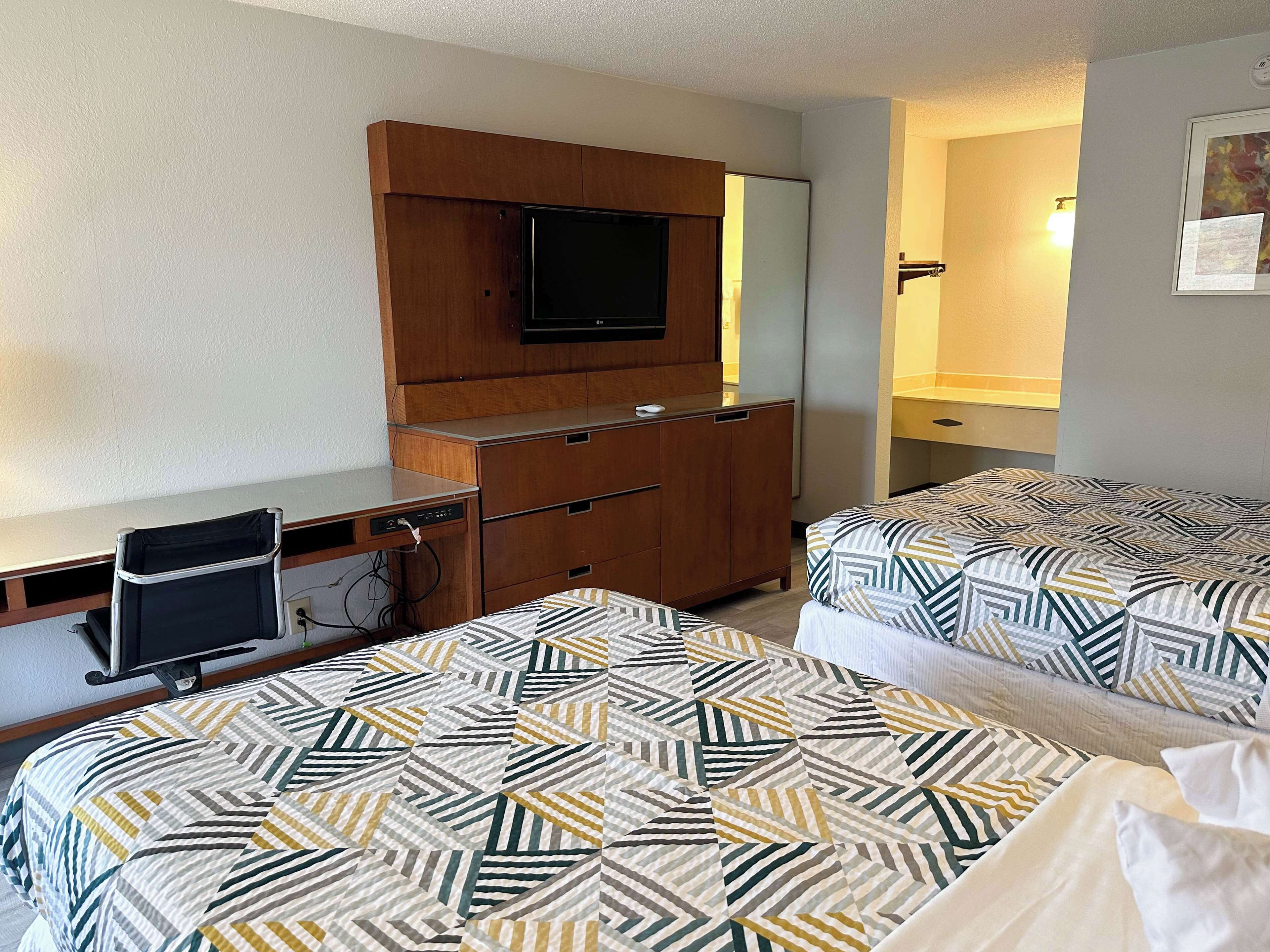 A hotel room with two beds, a desk, a TV, and a wardrobe.