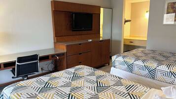 A hotel room with two beds, a desk, a TV, and a wardrobe.