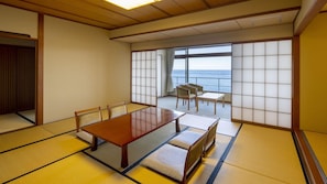 A traditional Japanese room with tatami flooring, a low table, and a view of the sea.