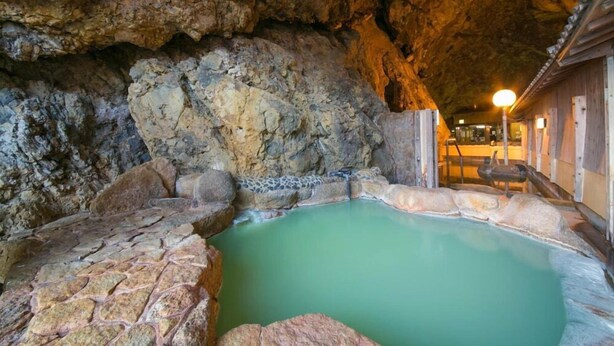 A hot spring area with a stone pool, wooden benches, and a lamp post. - Hotel Urashima (Nachikatsuura)
