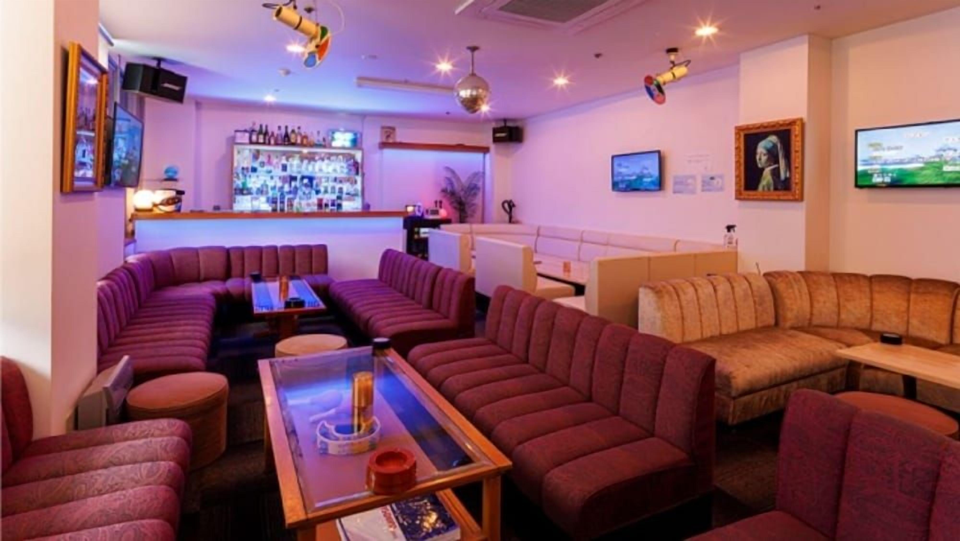A bar area with sofas, a bar counter, and a television screen.