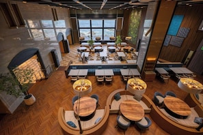 A modern interior with round tables and chairs, a fireplace, and a view of the ocean.