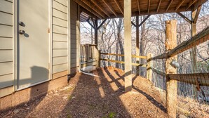 A covered outdoor area with a wooden structure, a fenced area, and a building with siding. - Cutest place ever! Fun Airline decor will make you smile! Huge deck! (Jasper)