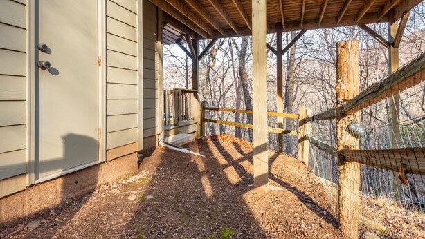 A covered outdoor area with a wooden structure, a fenced area, and a building with siding.