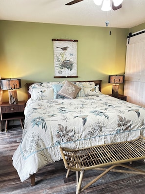 A bedroom with a bed, two bedside tables, a hanging lamp, a wall-mounted picture, and a ceiling fan. - Cutest place ever! Fun Airline decor will make you smile! Huge deck! (Jasper)