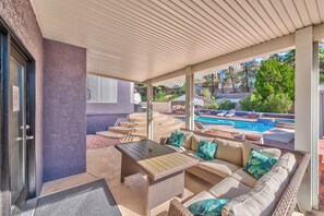 Un espacio de estar al aire libre cubierto, con vista a la piscina.