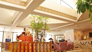 A hotel lobby with a reception desk, plush chairs, and a large indoor plant. - Sahoro Resort Hotel (Shintoku)