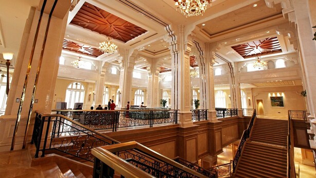 Un vestíbulo imponente con techos altos, candelabros ornamentales y una escalera central.