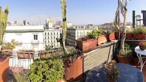 A rooftop garden with potted plants, a small table, and chairs. - Up Hotel (Naples)