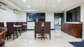 A spacious dining area with high ceilings, recessed lighting, and a view of the adjacent kitchen area. - Reddoorz @ Buah Batu (Bandung)