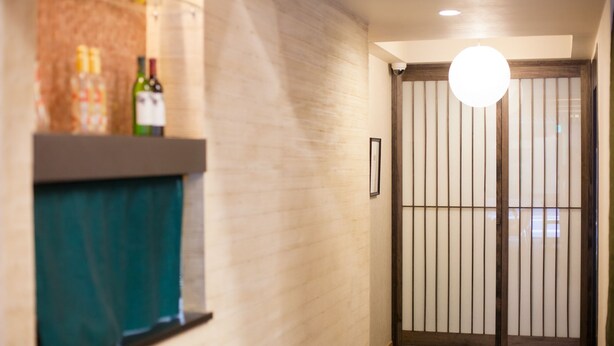Un pasillo con pared de madera, un cuadro enmarcado y una puerta con persianas verticales.