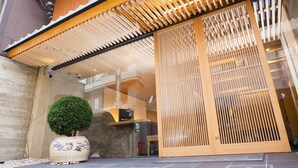 Un edificio de estilo japonés tradicional con una entrada de listones de madera y una planta en maceta.