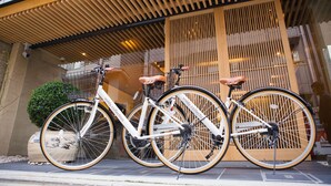 Tres bicicletas estacionadas frente a un edificio con una entrada de listones de madera.