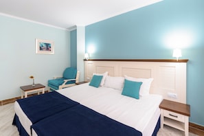 A hotel room with a bed, a chair, a nightstand, and a wall-mounted lamp. - Evridika (Nessebar)
