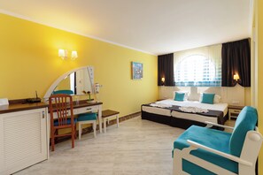 Quarto de hotel com uma cama, uma escrivaninha com cadeira, um espelho, uma janela com cortinas e um quadro na parede.