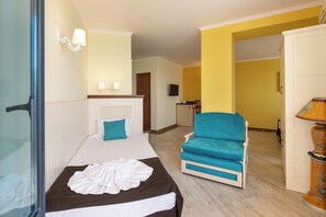 A hotel room with a bed, a chair, a lamp, and a television. - Evridika (Nessebar)