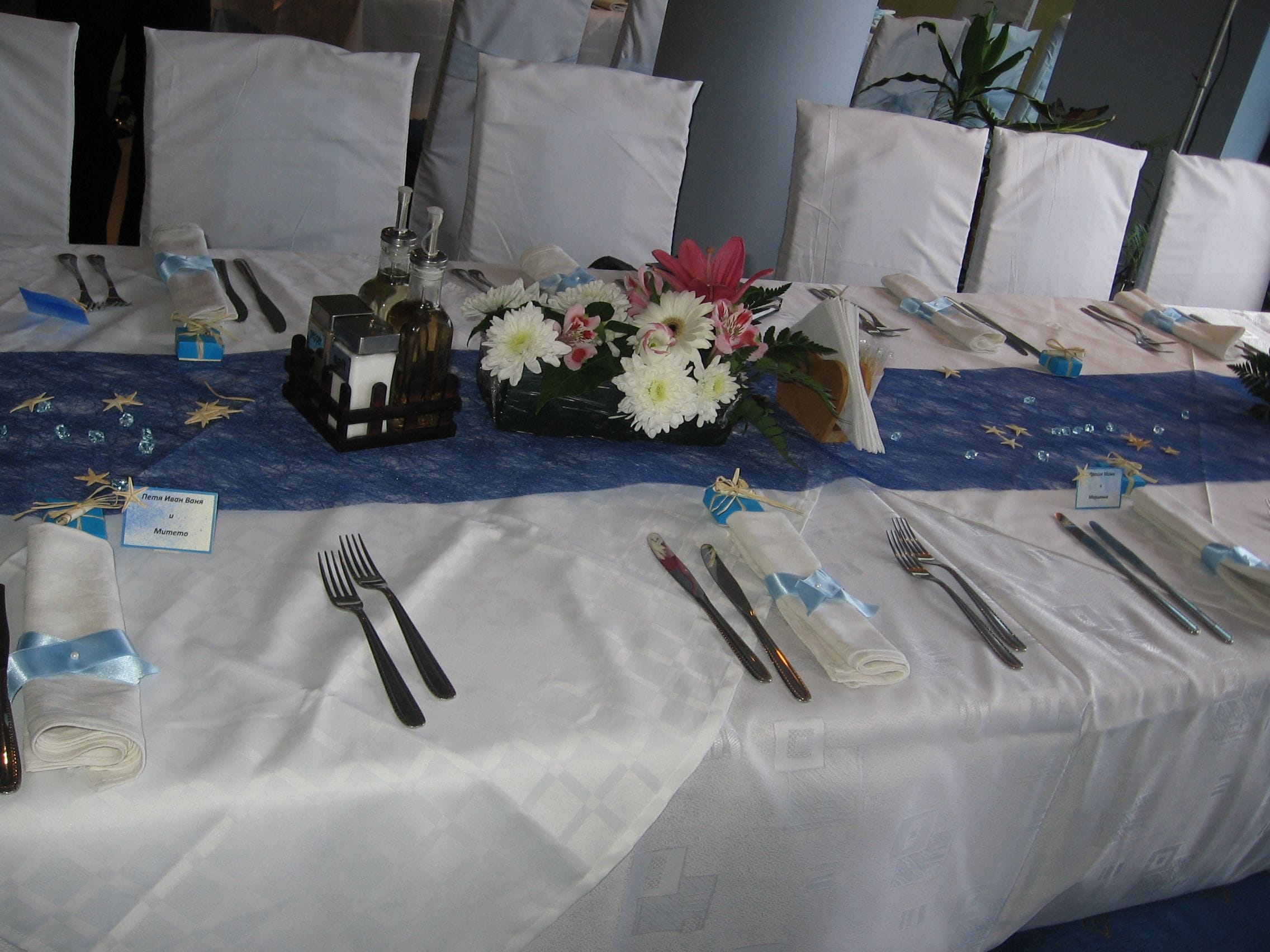 Ein gedeckter Tisch mit Besteck, einer Blumenvase und kleinen Geschenkkartons.