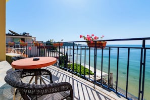 A balcony with a round table and chairs, potted plants, and a view of the sea. - Evridika (Nessebar)