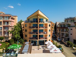 Un hotel de varios pisos con balcones, zona de estar exterior y piscina.