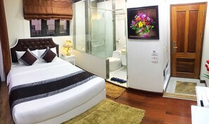Un dormitorio con cama, mesita de noche, lámpara y baño completo con ducha, inodoro y lavamanos.