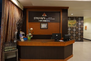 Ein Hotelrezeptionstresen mit Holzoptik, einem gerahmten Zertifikat und einem Computermonitor.