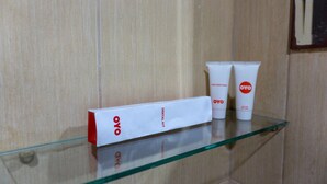 Une étagère en verre sur laquelle se trouve une boîte blanche portant l’inscription « OYO » et deux tubes blancs avec des logos rouges.
