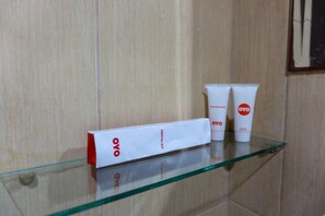 Een glazen plank met een witte doos met daarop 'OYO' en twee witte tubes met rode logo's.