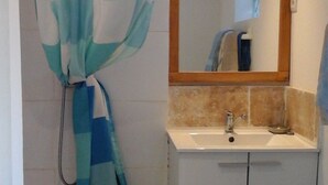 Ein Badezimmer mit Duschvorhang, Waschbecken, Spiegel und Toilette.