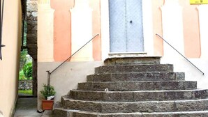 A set of stone steps leading to a door with a blue shutter, flanked by walls with a light peach color.