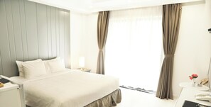 A hotel bedroom with a bed, bedside table, lamp, and curtains.
