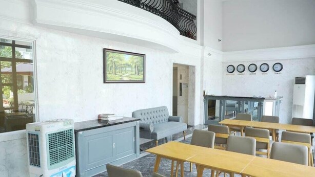 A room with a sofa, tables, and a fireplace. There are clocks on the wall and an air conditioning unit. - Fide Hotel (Ho Chi Minh Municipality)