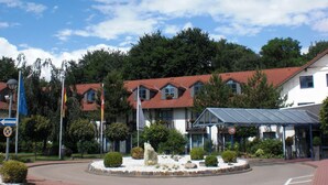 A hotel with multiple buildings, a roundabout, and a clear sky. - Landhotel Schnuck (Schneverdingen)