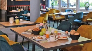 A breakfast setup with tables, chairs, and a variety of breakfast items. - Landhotel Schnuck (Schneverdingen)