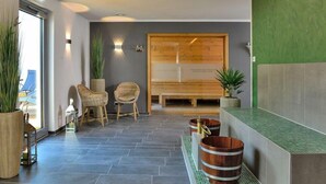 A reception area with a wooden reception desk, two wicker chairs, a bench, and a green wall. - Landhotel Schnuck (Schneverdingen)