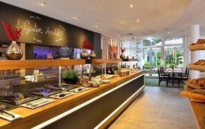 Un'area buffet con diversi cibi, un cartello con la scritta 'Guten Appetit!' e un angolo relax con tavoli e sedie.