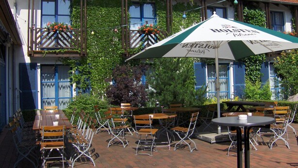 A traditional European-style building with outdoor seating and a large umbrella. - Landhotel Schnuck (Schneverdingen)