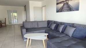 Una sala de estar moderna con un sofá seccional gris, una mesita de centro blanca y un cuadro de un muelle en la pared.