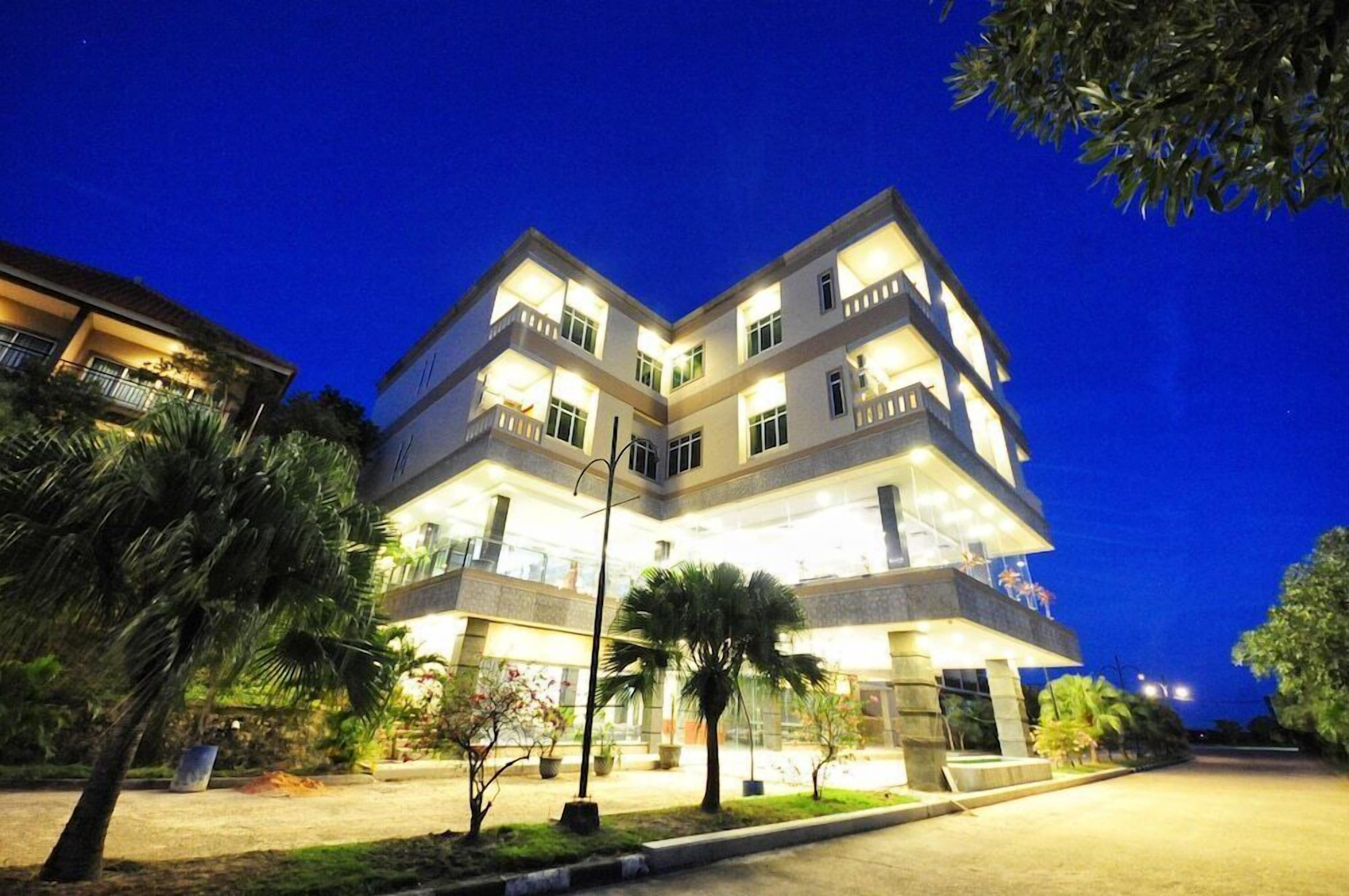 A multi-story hotel with a central courtyard, balconies, and a well-lit exterior.