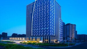 A modern high-rise building with a grid-like facade and a prominent entrance area with illuminated railings. - Wanda Vista Zhengzhou (Zhengzhou)