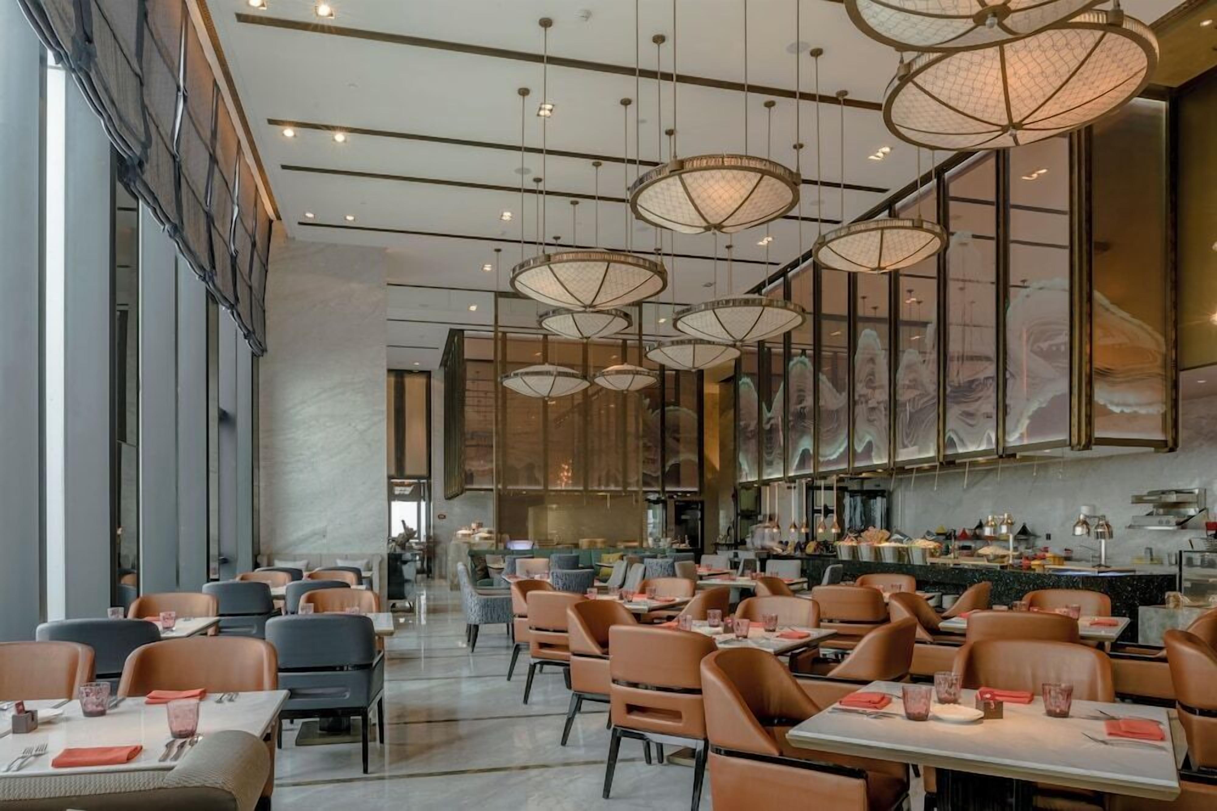 A spacious restaurant with high ceilings, modern pendant lighting, and a long counter.