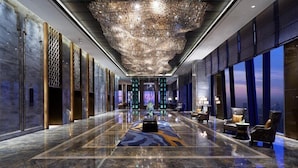 A spacious lobby with a reflective floor, a large chandelier, and seating areas with views of the city. - Wanda Vista Zhengzhou (Zhengzhou)