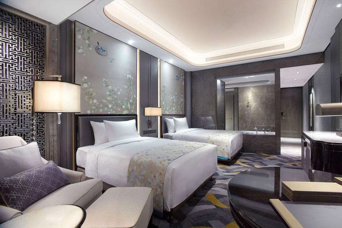 Une chambre d’hôtel moderne avec deux lits, un bureau et une salle de bain.